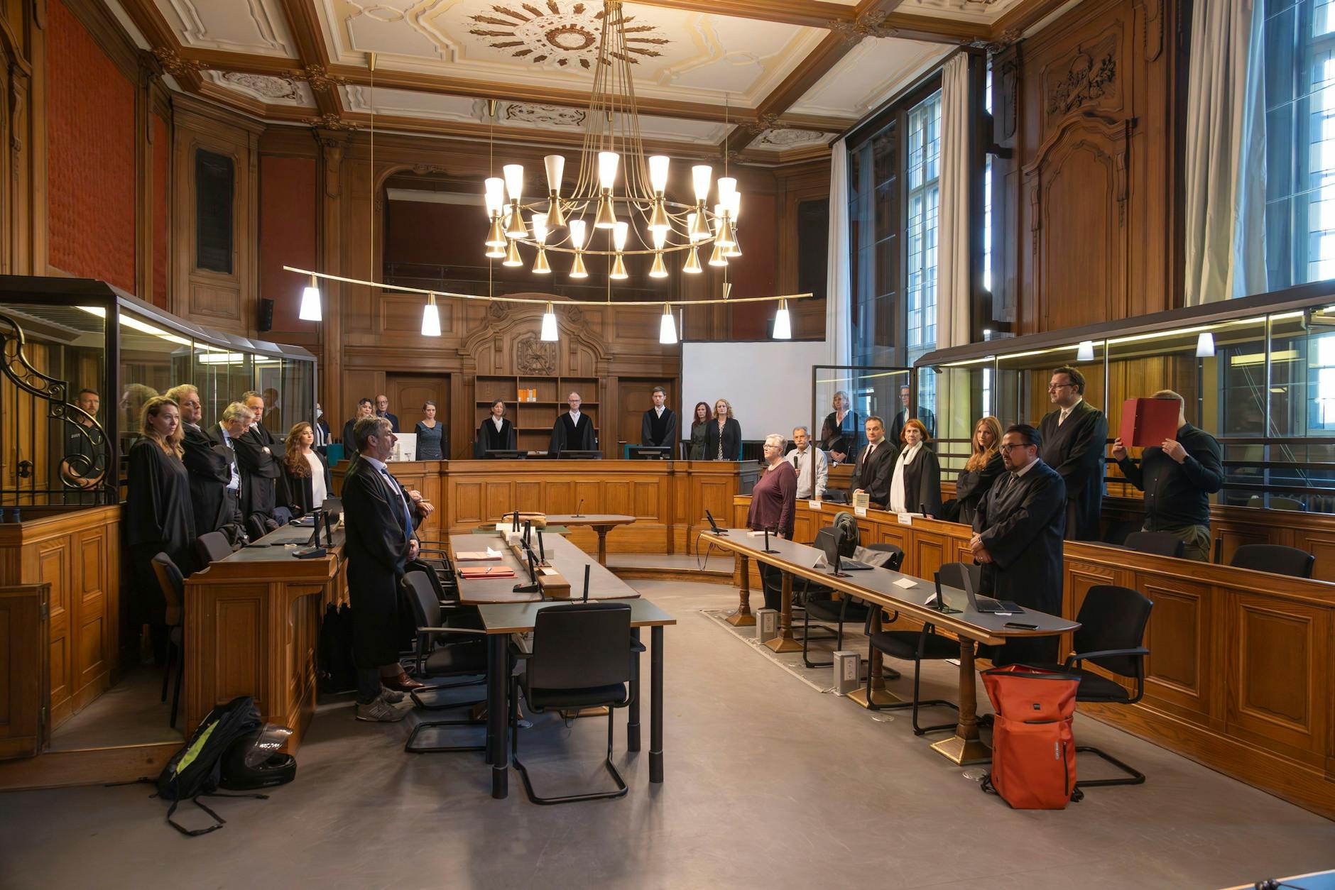 Rechts mit der roten Mappe steht einer der Angeklagten in dem Prozess um Steuerhinterziehung.