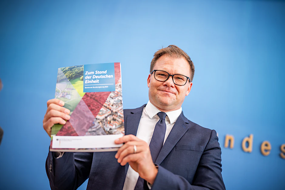 Carsten Schneider (SPD), Staatsminister und Ostbeauftragter der Bundesregierung, zeigt den Bericht „Zum Stand der Deutschen Einheit“. Am 3. Oktober jährt sich die deutsche Wiedervereinigung zum 33. Mal.
