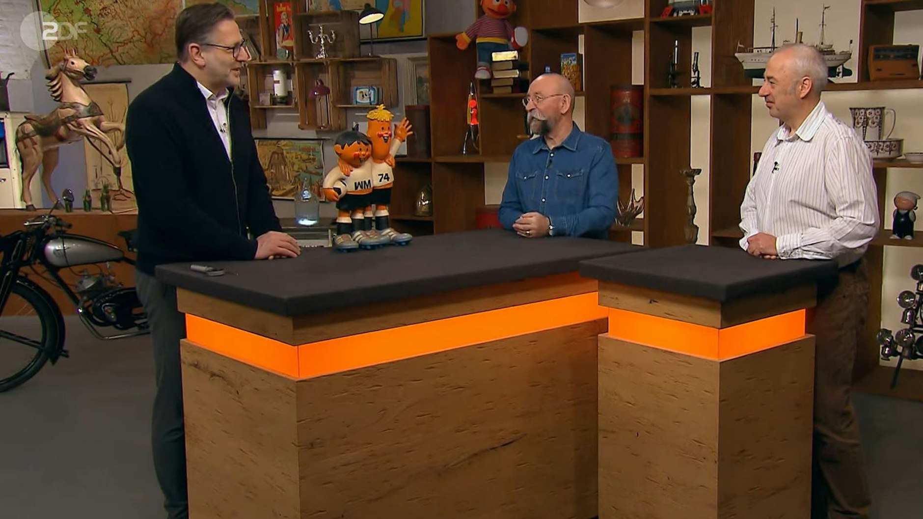 Der „Bares für Rares“-Experte Detlev Kümmel (li.) mit Fußballgeschichte sowie der Moderator Horst Lichter und der Verkäufer Michael
