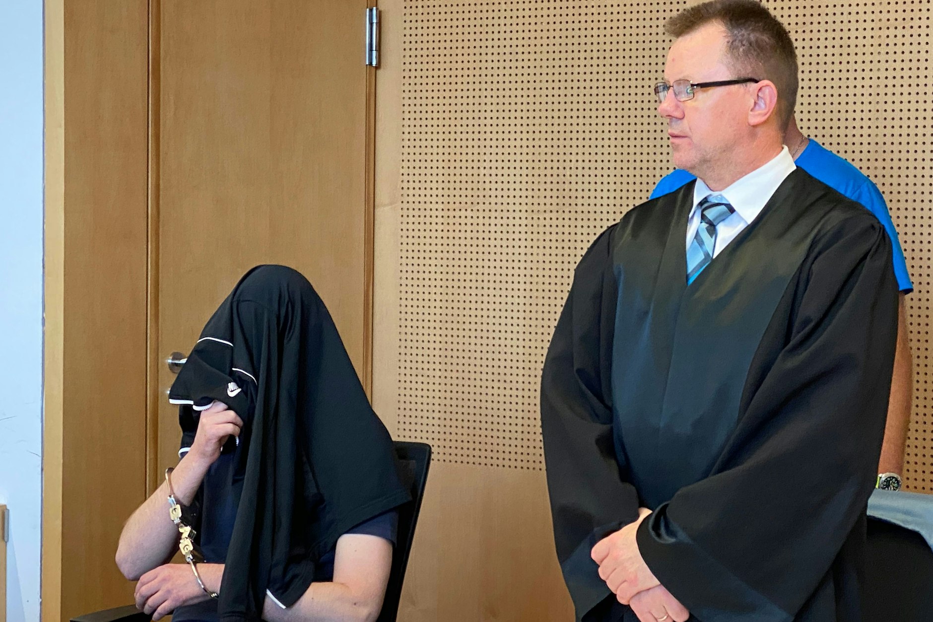 Stephan D. wird in Handschellen in den Saal geführt. Neben ihm steht Artur Ragwitz, sein Anwalt.