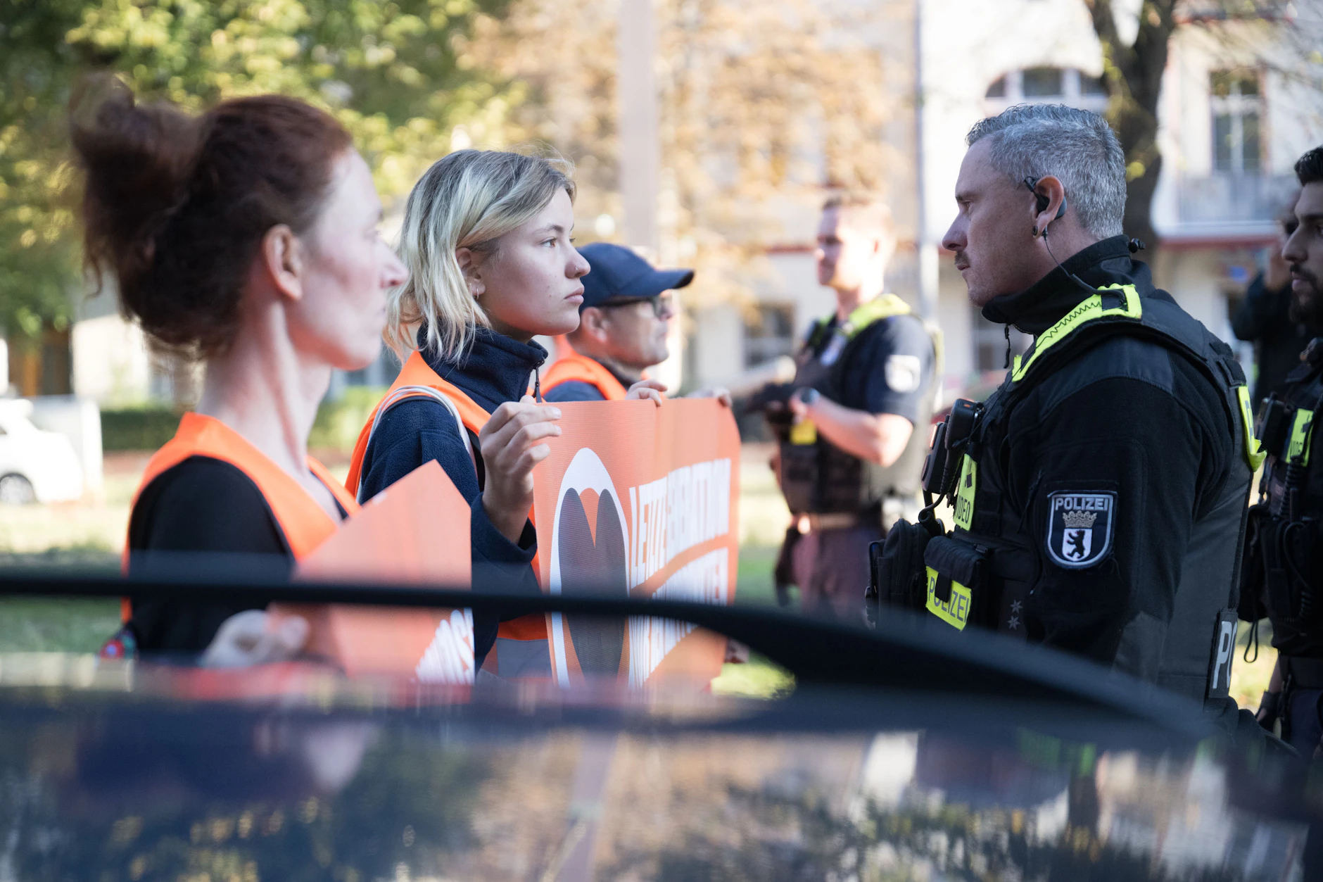 Aktivisten der Letzten Generation stehen während einer Laufblockade auf der Bornholmer Straße vor Polizeibeamten.