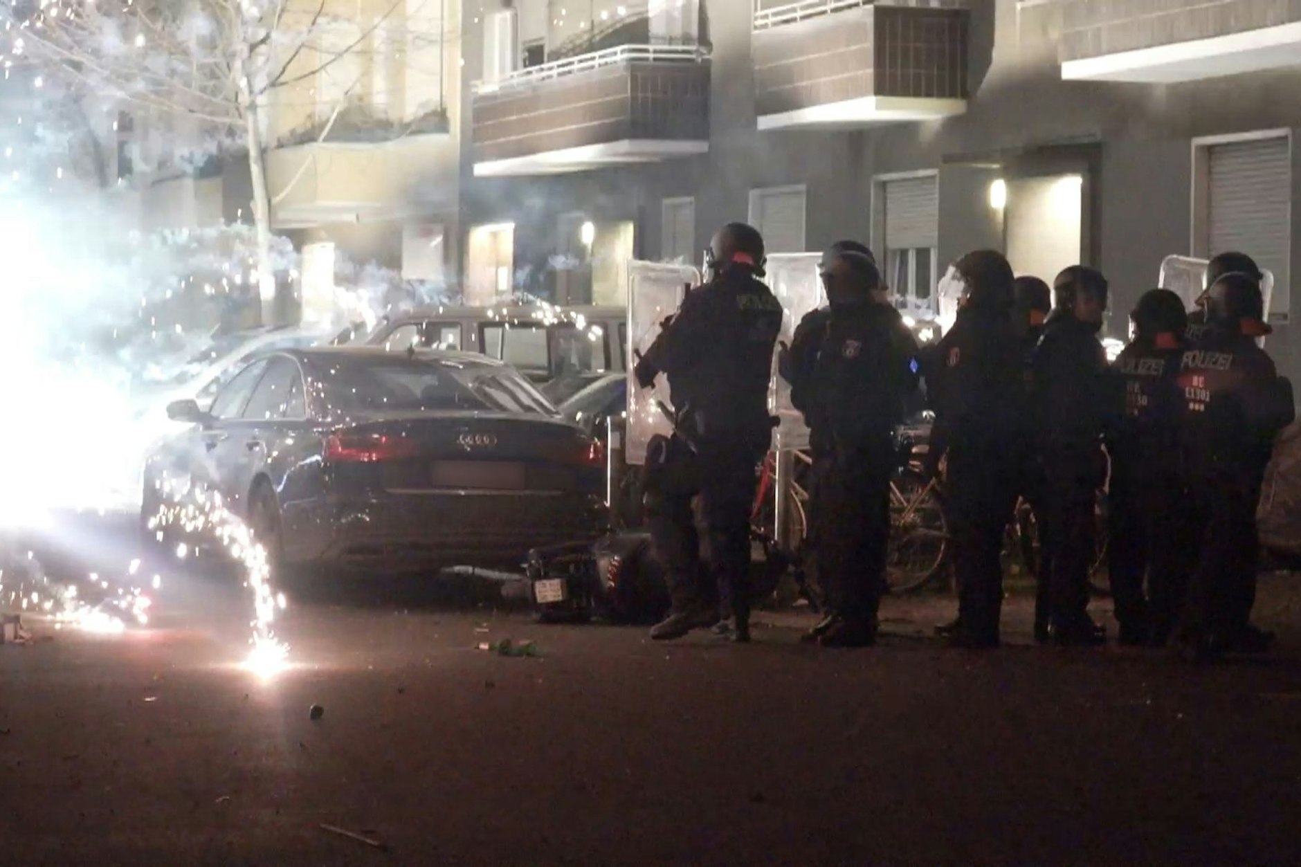 Polizeibeamte hinter explodierendem Feuerwerk in Berlin. Nach Angriffen auf Einsatzkräfte läuft die Diskussion um Konsequenzen.