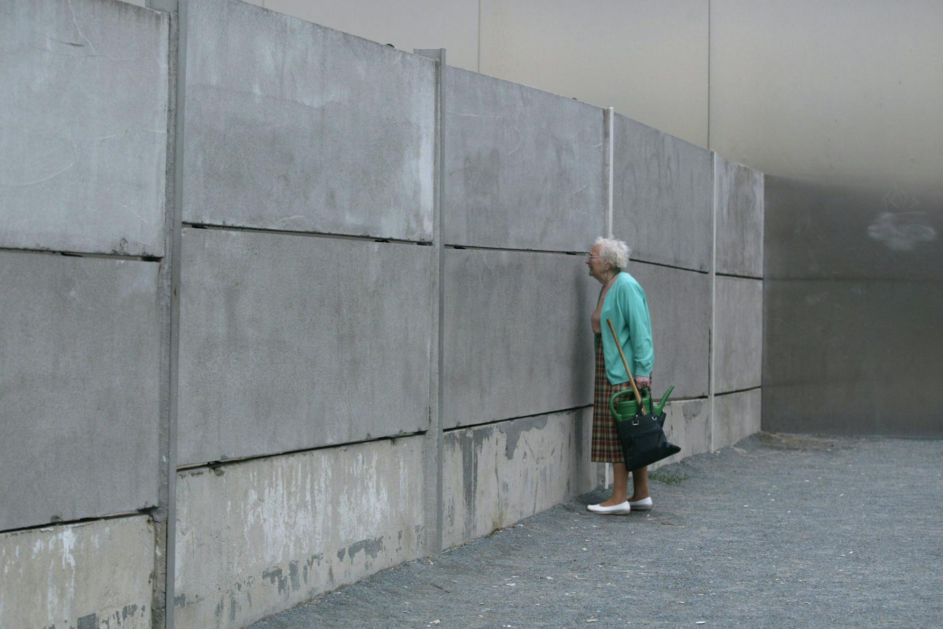 Eine ältere Frau schaut an der Gedenkstätte in der Bernauer Straße in die abgesperrte Grenzanlage.