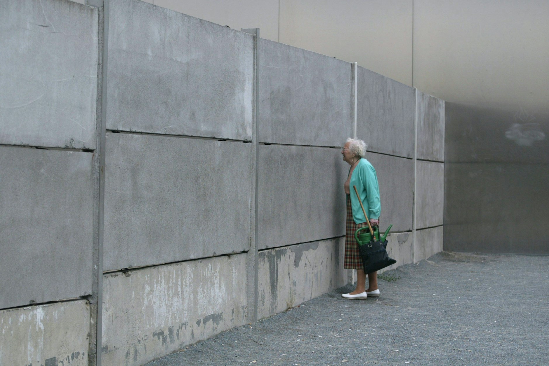 Eine ältere Frau schaut an der Gedenkstätte in der Bernauer Straße in die abgesperrte Grenzanlage.