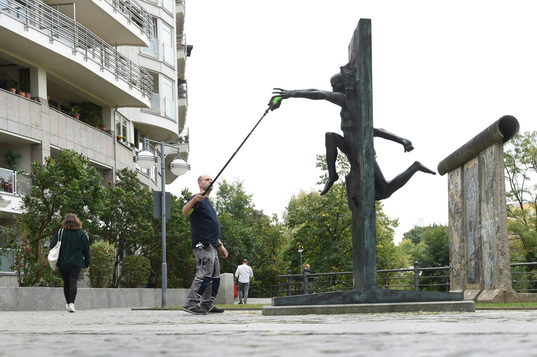 Ein Mann putzt die Skulptur „Wir sind das Volk“.