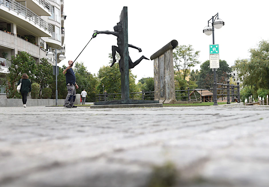 Ein Mann putzt die Skulptur „Wir sind das Volk“.