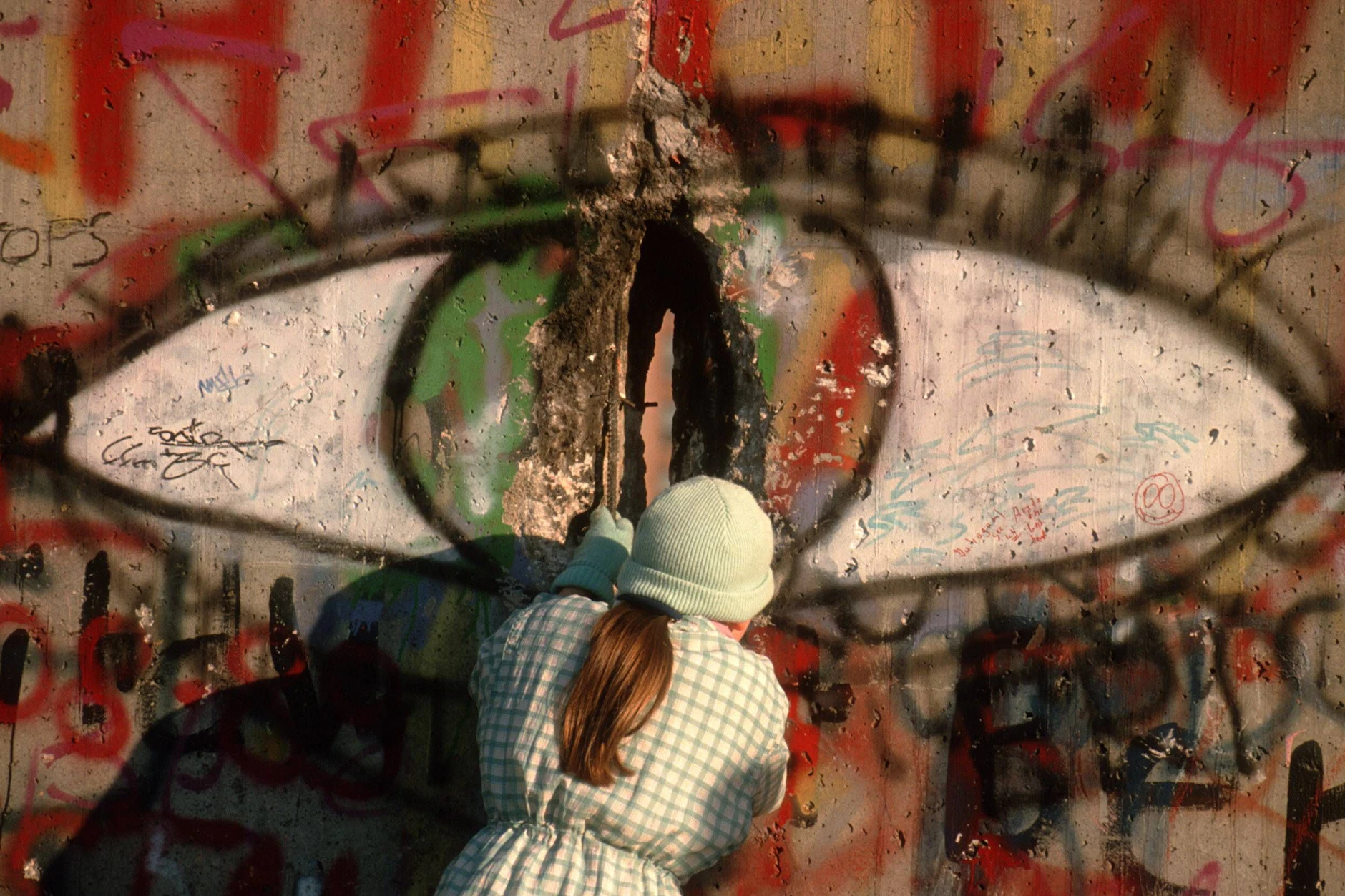 Eine Frau meisselt ein Stück aus der Berliner Mauer.