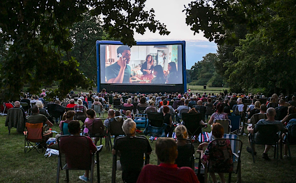 PRODUKTION - Zahlreiche Zuschauer verfolgen im Freiluftkino einen Film.  