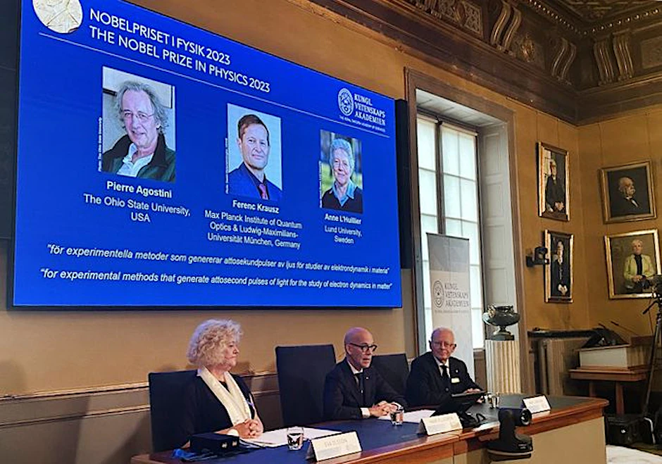 Schweden, Stockholm: Auf der Projektion während der Bekanntgabe des Nobelpreises für Physik sind die Wissenschaftler Pierre Agostini, Ferenc Krausz und Anne L'Huillier zu sehen.