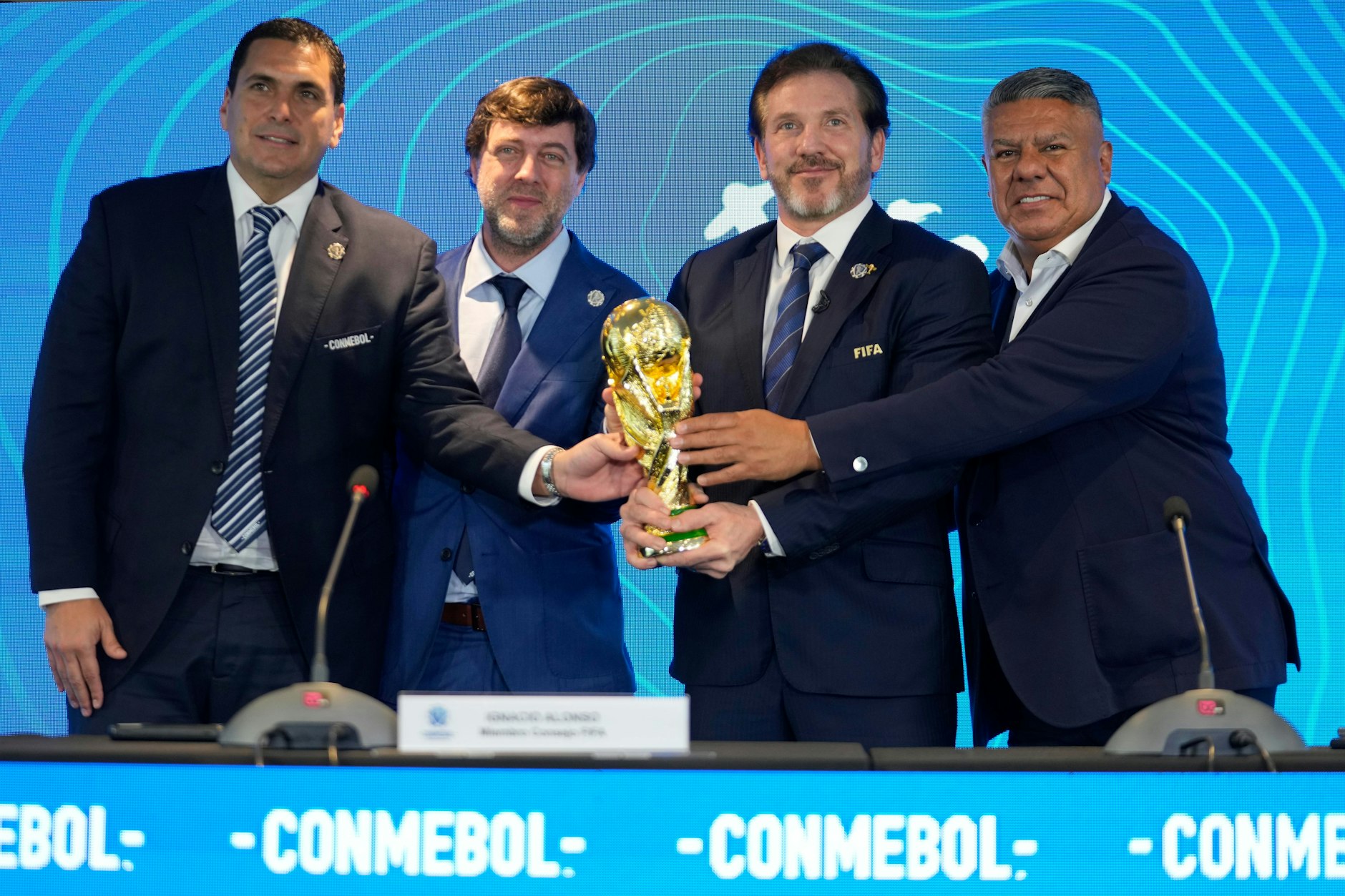 Robert Harrison (l-r), Paraguays Fußballverbandspräsident, Ignacio Alonso, FIFA-Delegierter, Alejandro Dominguez, Conmebol-Präsident und Conmebol-Vizepräsident Claudio Tapia halten den Pokal der Fußballweltmeisterschaft. Auf der Pressekonferenz wurde überraschend bekann gegeben, dass einige Spiele der Fußballweltmeisterschaft 2030 in Argentinien, Uruguay und Paraguay ausgetragen werden. 