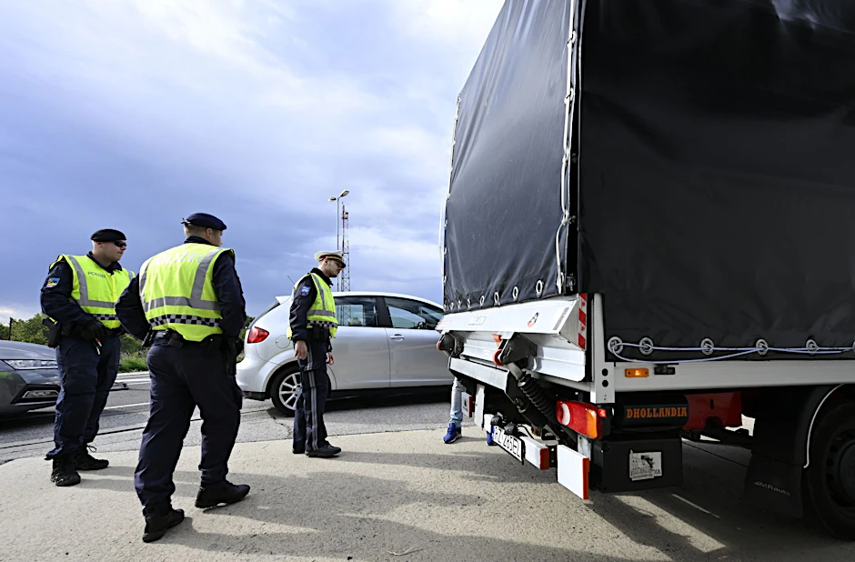 Polizisten kontrollieren einen Lastwagen und Autofahrer am Grenzübergang Berg in Österreich.  