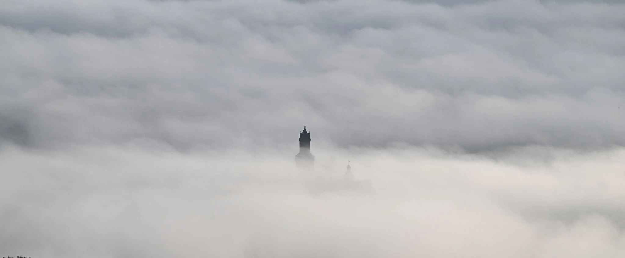 Nur die Spitze des Freiturms der Burg Kronberg im hessischen Königstein ragt aus der Wolkenschicht heraus.  