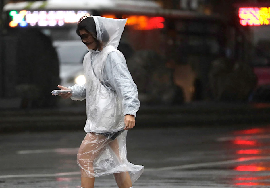 Eine Frau läuft bei Regen und Wind durch Taipeh.  