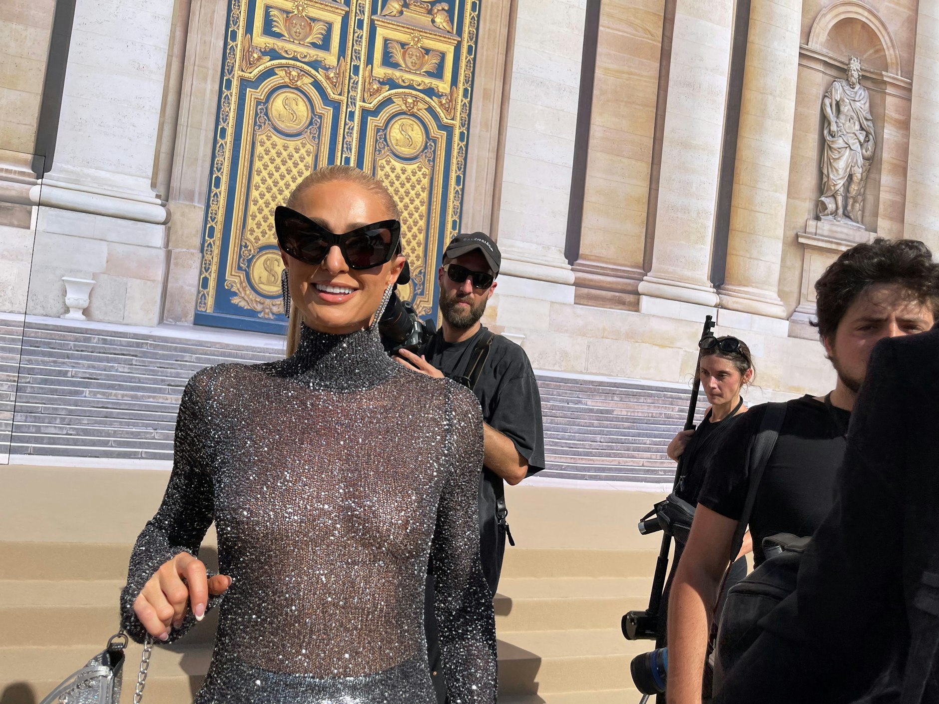 Paris Hilton ist ein Vollprofi. Ausgiebig ließ sie sich in der prallen Sonne fotografieren, ohne mit der Wimper zu zucken – hier im hochgeschlossenen Balenciaga-Glitzerfummel. Bravo!
