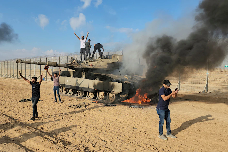 Palästinenser feiern an einem zerstörten israelischen Panzer am Zaun des Gazastreifens östlich von Khan Younis.