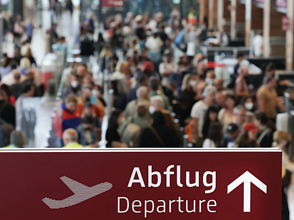 ARCHIV - Am Flughafen Berlin Brandenburg BER stehen zahlreiche Reisende in einer Schlange.  