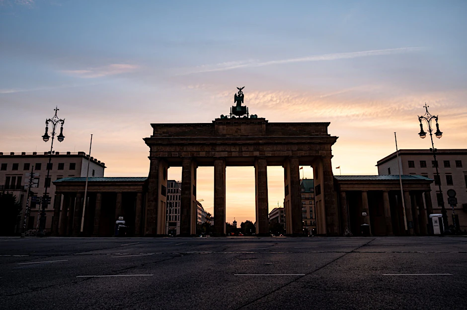 Die Wolken hinter dem Brandenburger Tor sind hell erleuchtet.  