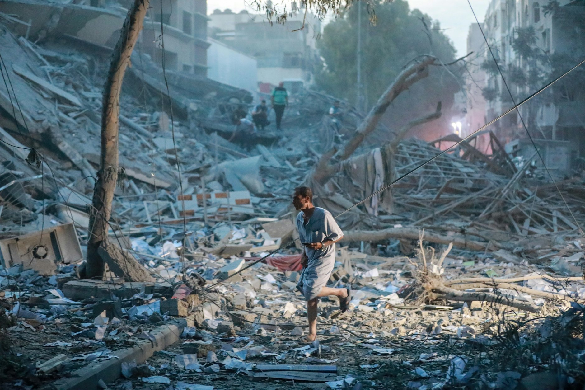 Menschen halten sich auf den Trümmern eines Turms auf, der bei einem israelischen Luftangriff in Gaza-Stadt zerstört wurde.