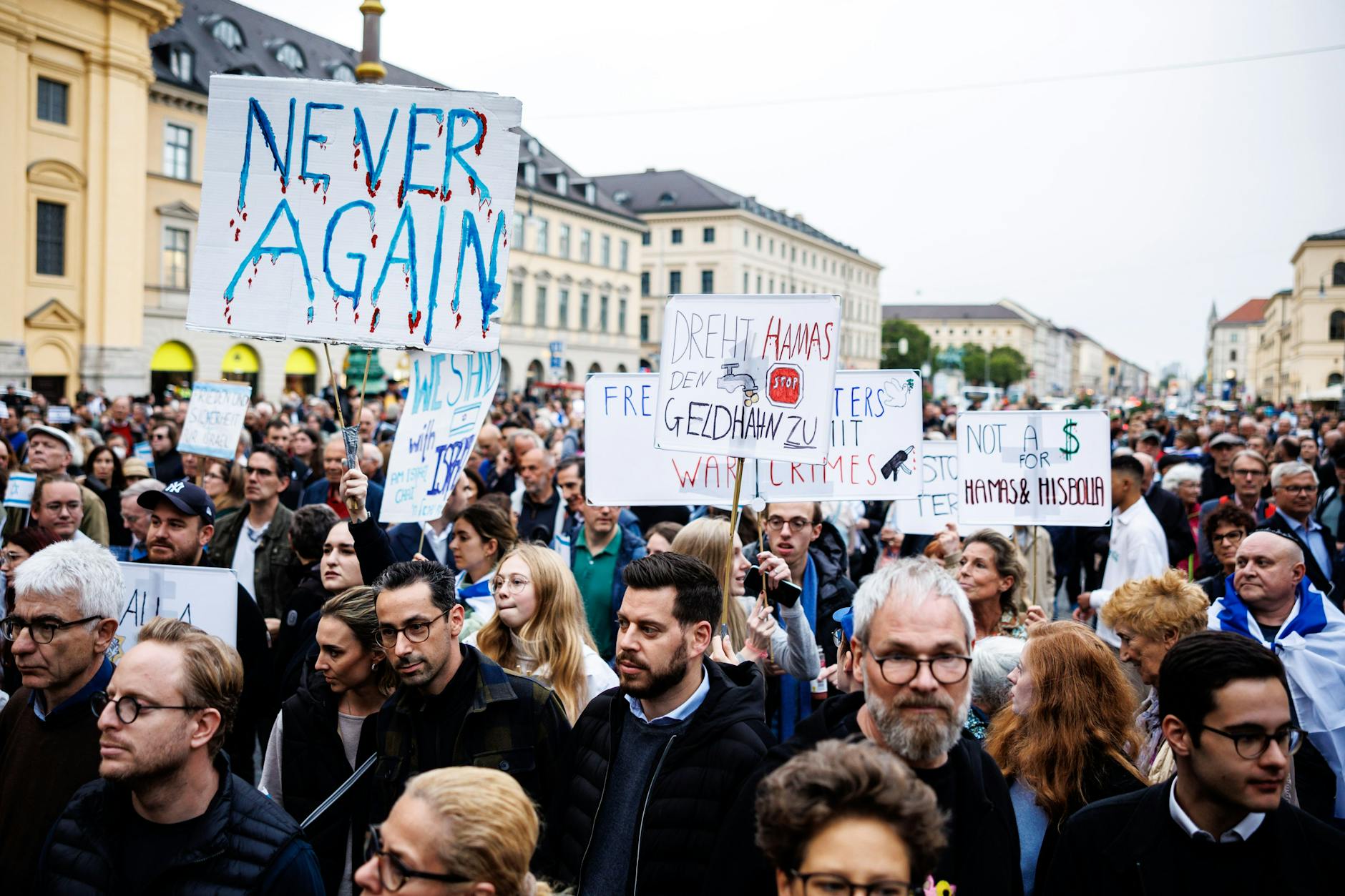 Teilnehmer einer Demonstration in München halten Schilder mit Aufschriften wie „Never again“ oder „Dreht Hamas den Geldhahn zu“.
