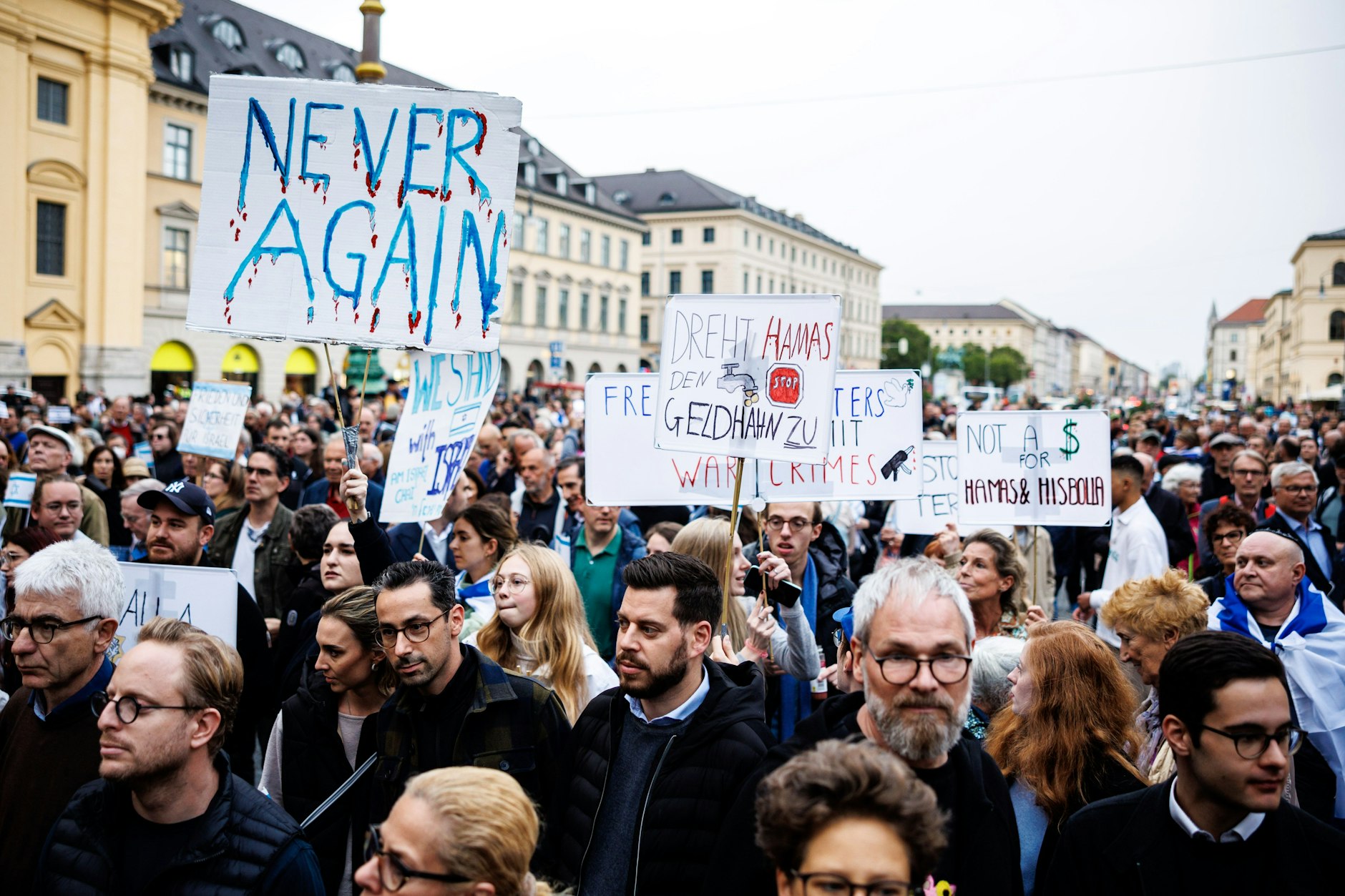 Teilnehmer einer Demonstration in München halten Schilder mit Aufschriften wie „Never again“ oder „Dreht Hamas den Geldhahn zu“.