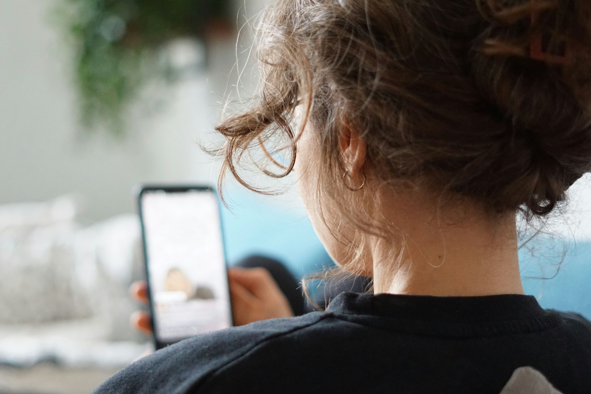 Gebraucht und gut: Eine Frau liegt auf einem Sofa und schaut sich ein Video auf ihrem Handy an.