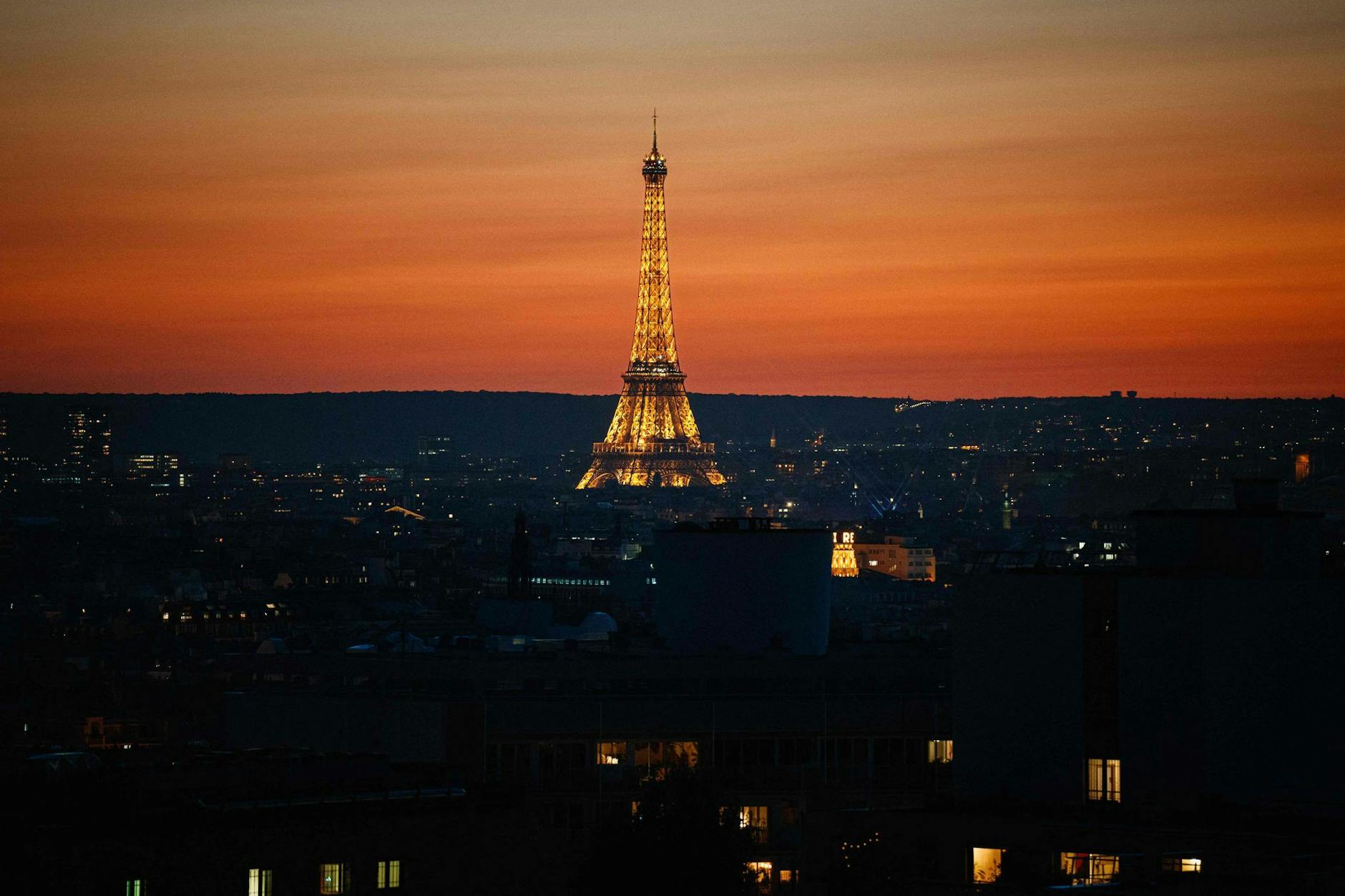 Beim Sonnenuntergang in Paris leuchtet der Eiffelturm, das Wahrzeichen der französischen Hauptstadt, in goldenem Licht.