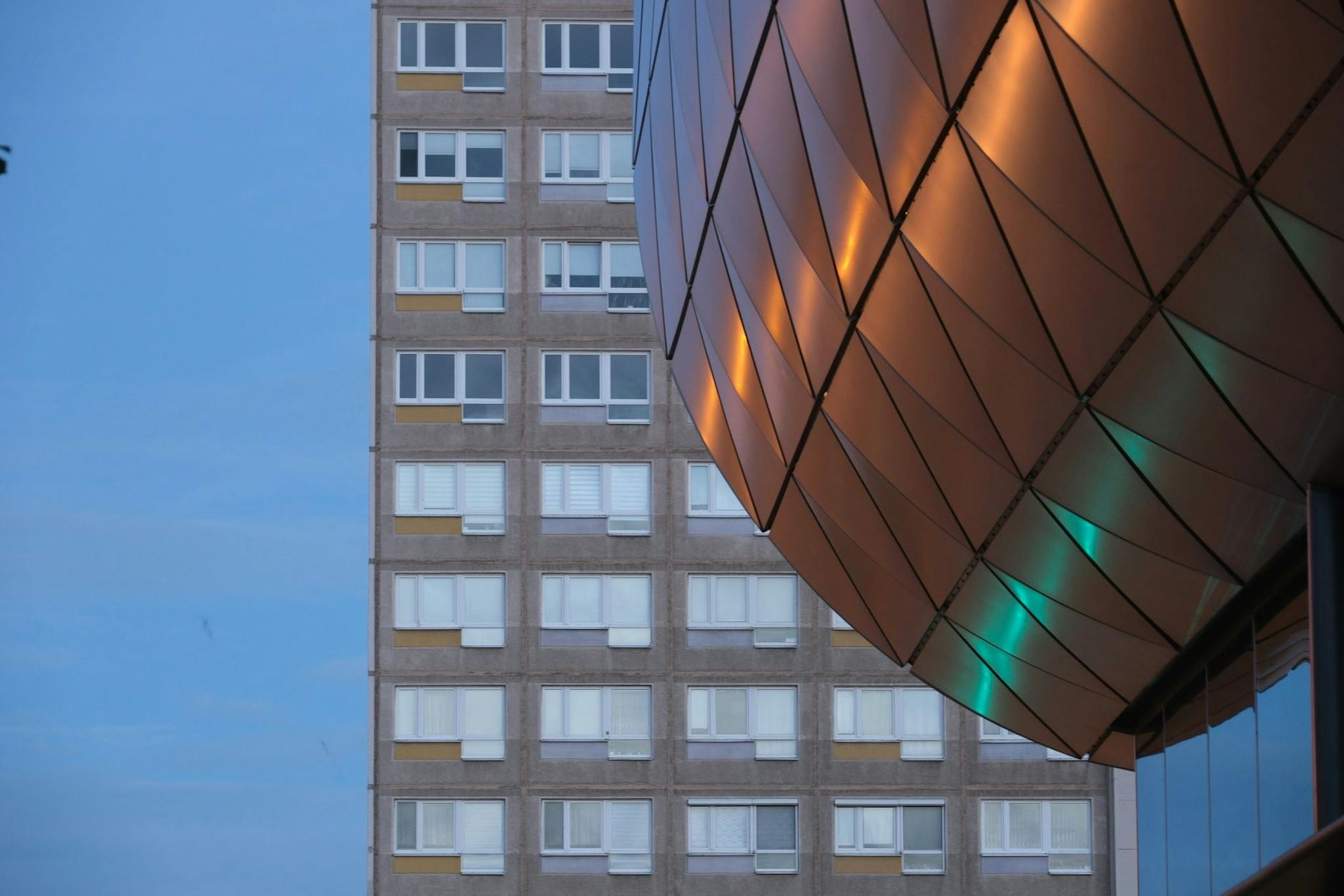 Fassadenlemente des Neubaues der Deutschen Nationalbibliothek in Leipzig vor einem Plattenbau aus DDR-Zeiten.