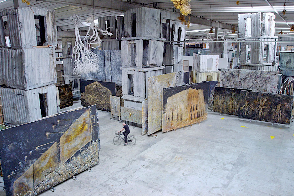 Der Künstler Anselm Kiefer radelt durch eines seiner Hallen-Ateliers. Szene aus „Anselm&nbsp;–&nbsp;Das Rauschen der Zeit“.