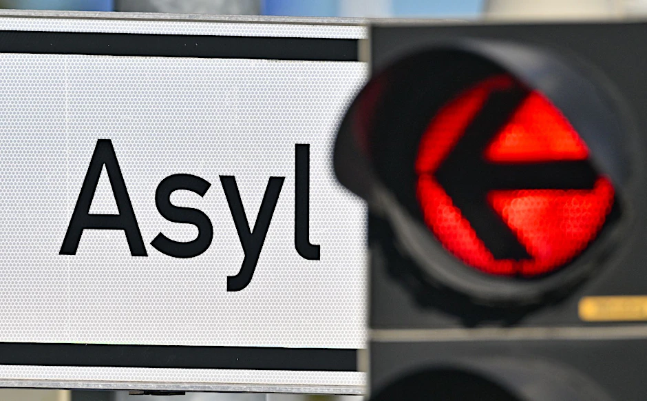 ARCHIV - Eine rote Ampel leuchtet vor dem Wort «Asyl» auf einem Wegweiser.  