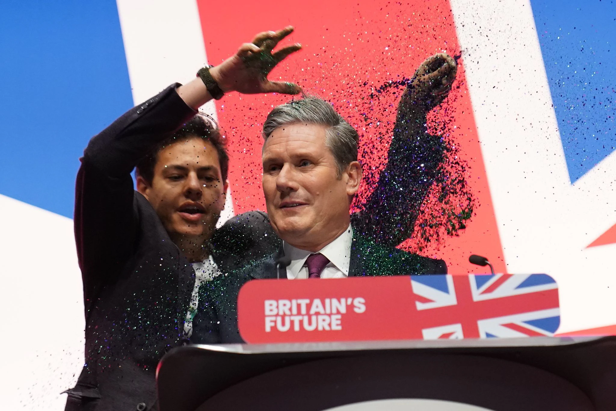 dpatopbilder - Ein Demonstrant bestreut den Vorsitzenden der britischen Labour-Partei, Keir Starmer, bei seiner Grundsatzrede auf dem Parteitag mit Glitzer.  