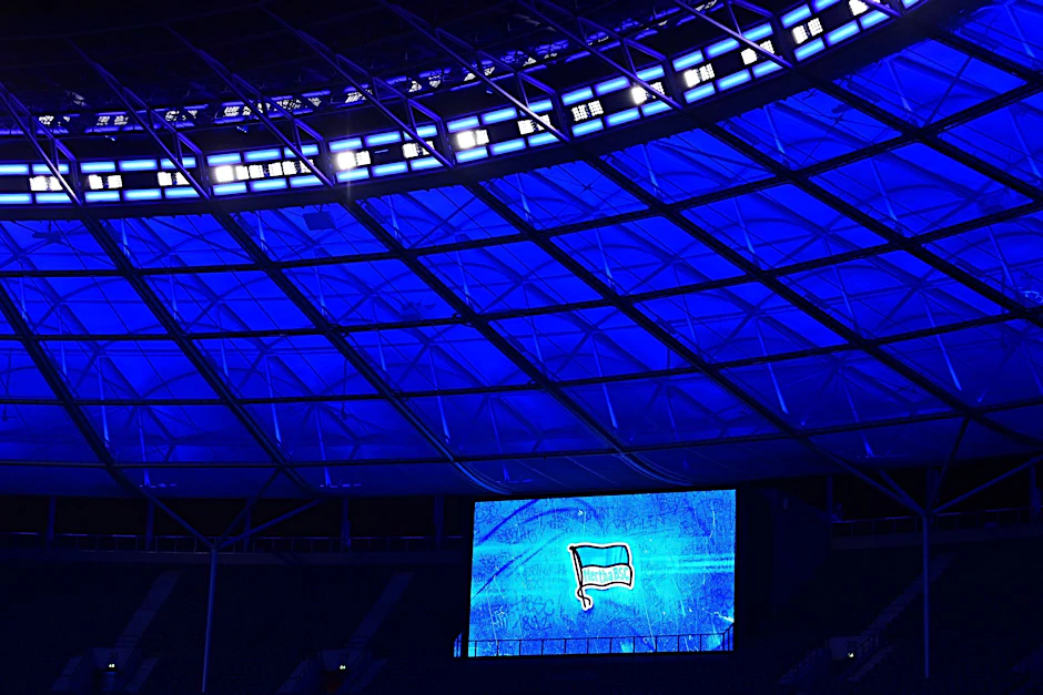 Eine Anzeigentafel im Olympiastadion zeigt vor einem Spiel die Fahne von Hertha BSC an.  
