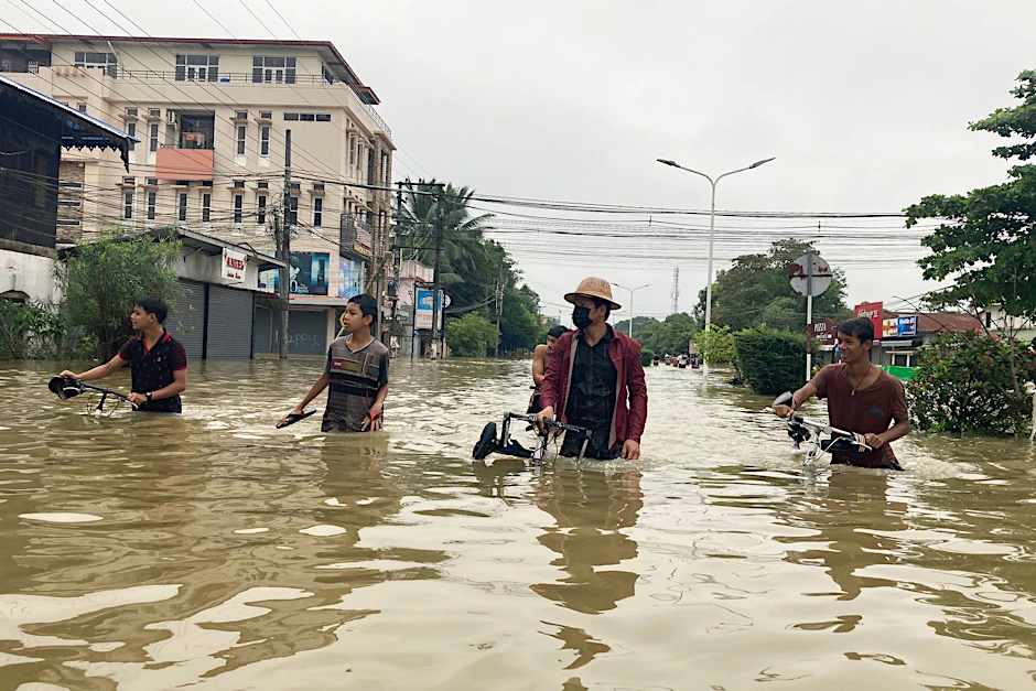 Anwohner schieben ihre Fahrräder durch eine überschwemmte Straße in Bago.  