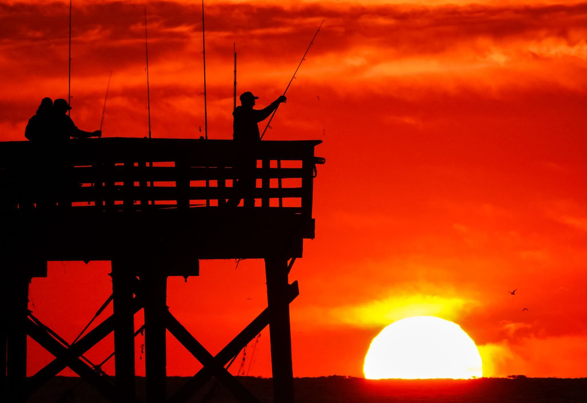 Angler stehen bei Sonnenaufgang am Sea Cabins Pier auf der Isle of Palms im US-Bundesstaat South Carolina.  a