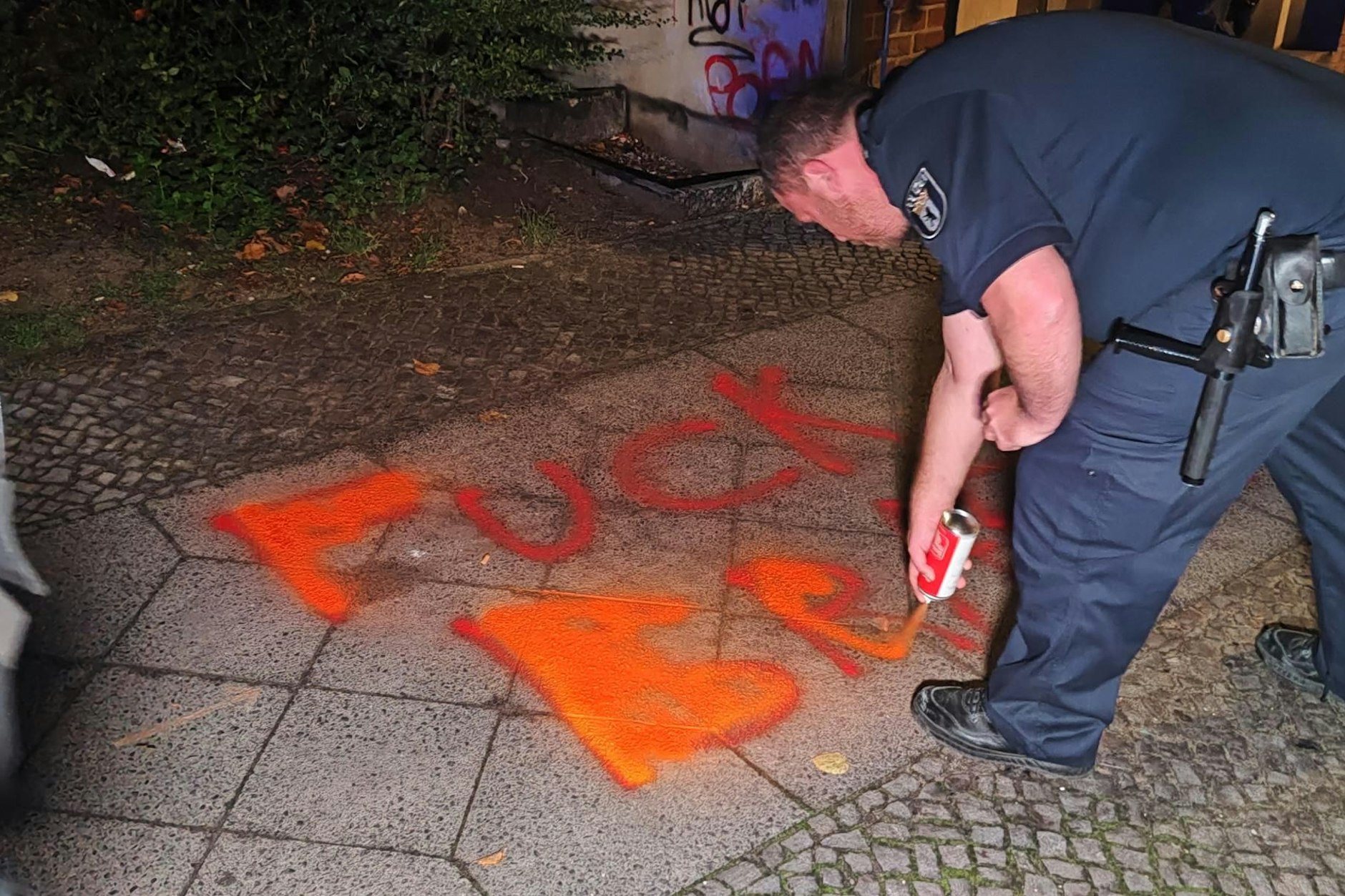 Hass-Parole auf einem Gehweg in Neukölln: Ein Polizist übersprüht sie mit Kreidespray.