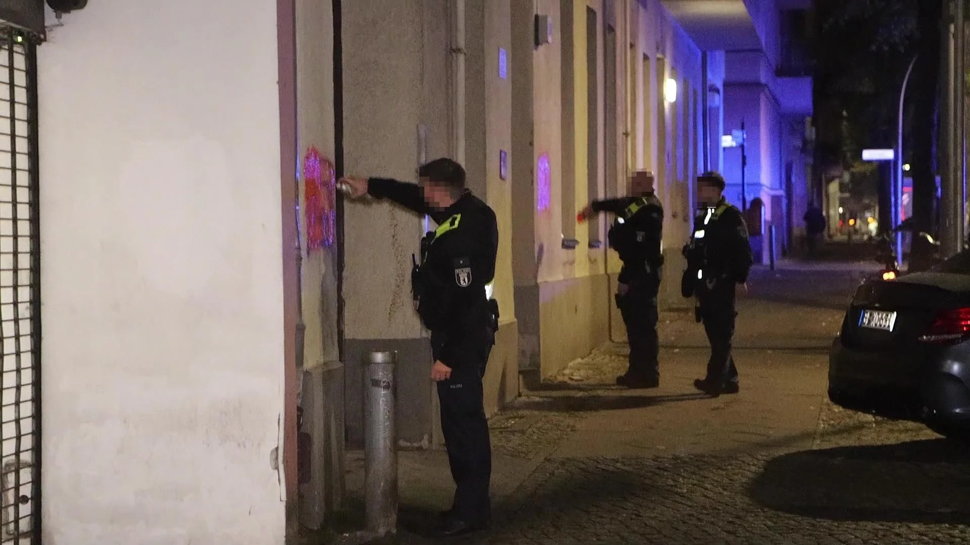 Polizisten entfernen in Neukölln Hass-Parolen von den Hauswänden.