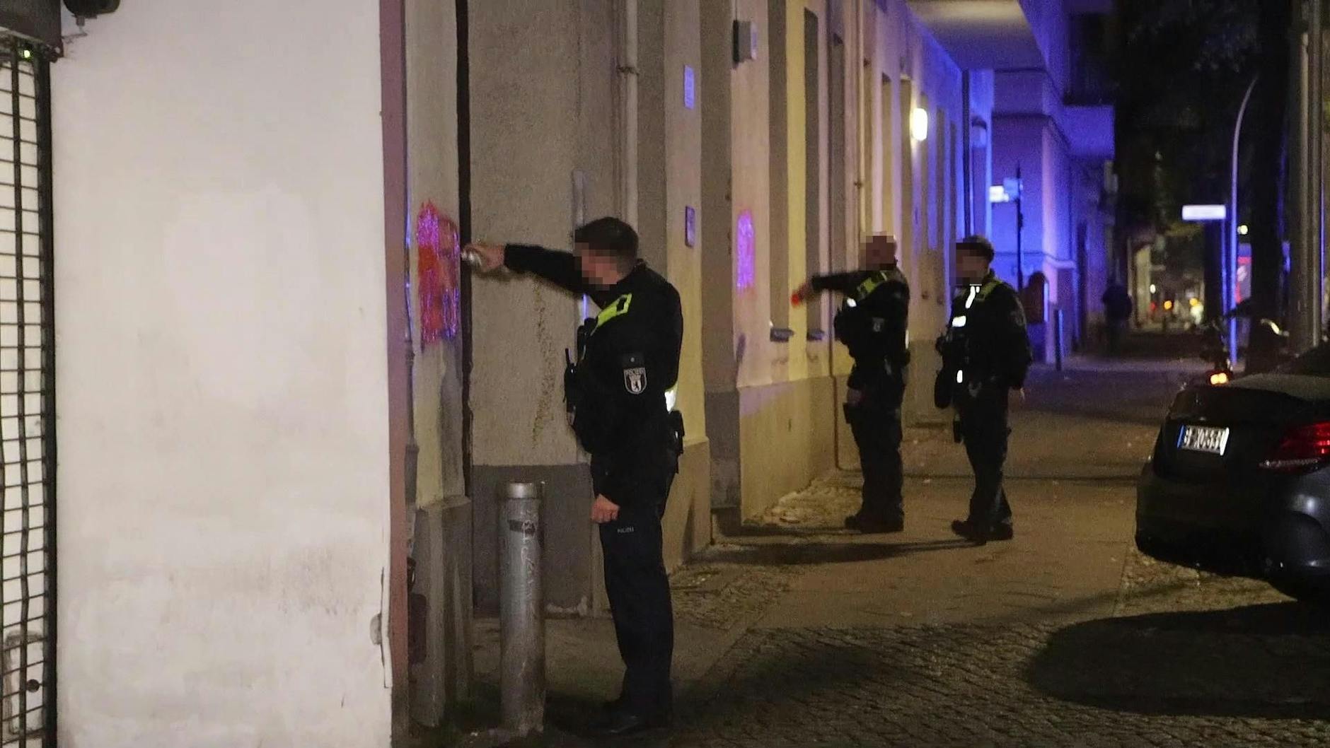 Polizisten entfernen in Neukölln Hass-Parolen von den Hauswänden.
