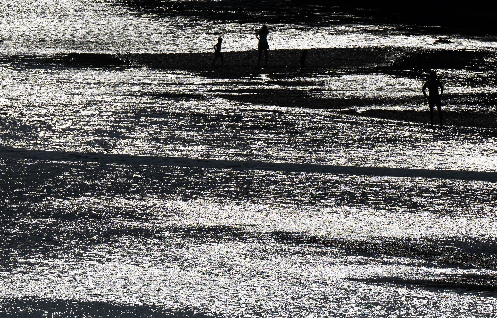 Ausflügler genießen das schöne Wetter in München am Ufer der Isar.  