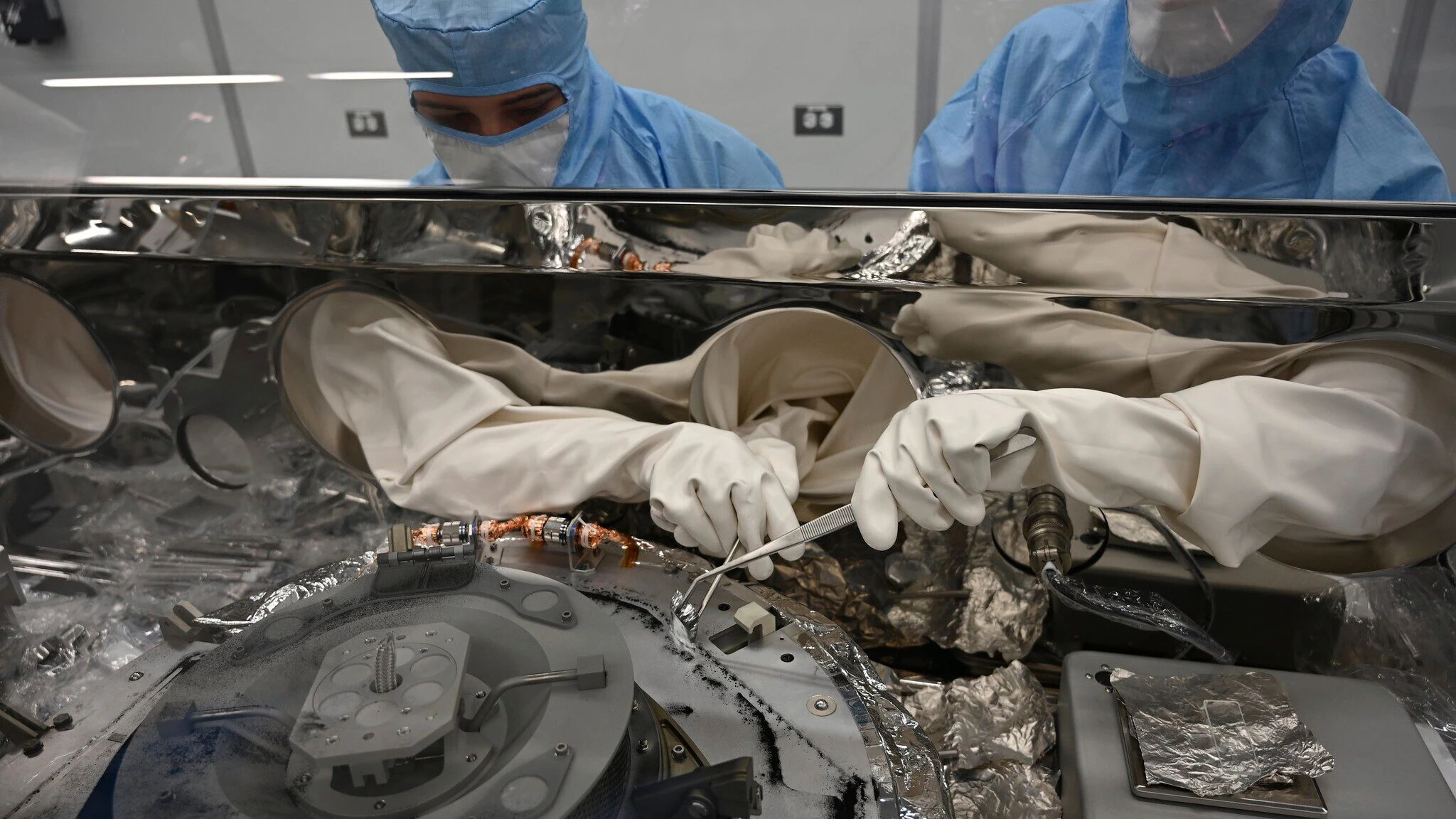 Auf diesem von der NASA zur Verfügung gestellten Foto verwenden Mari Montoya (l) und Curtis Calva im Johnson Space Center in Houston Werkzeuge, um Asteroidenpartikel von der Basis eines Behälters zu sammeln.