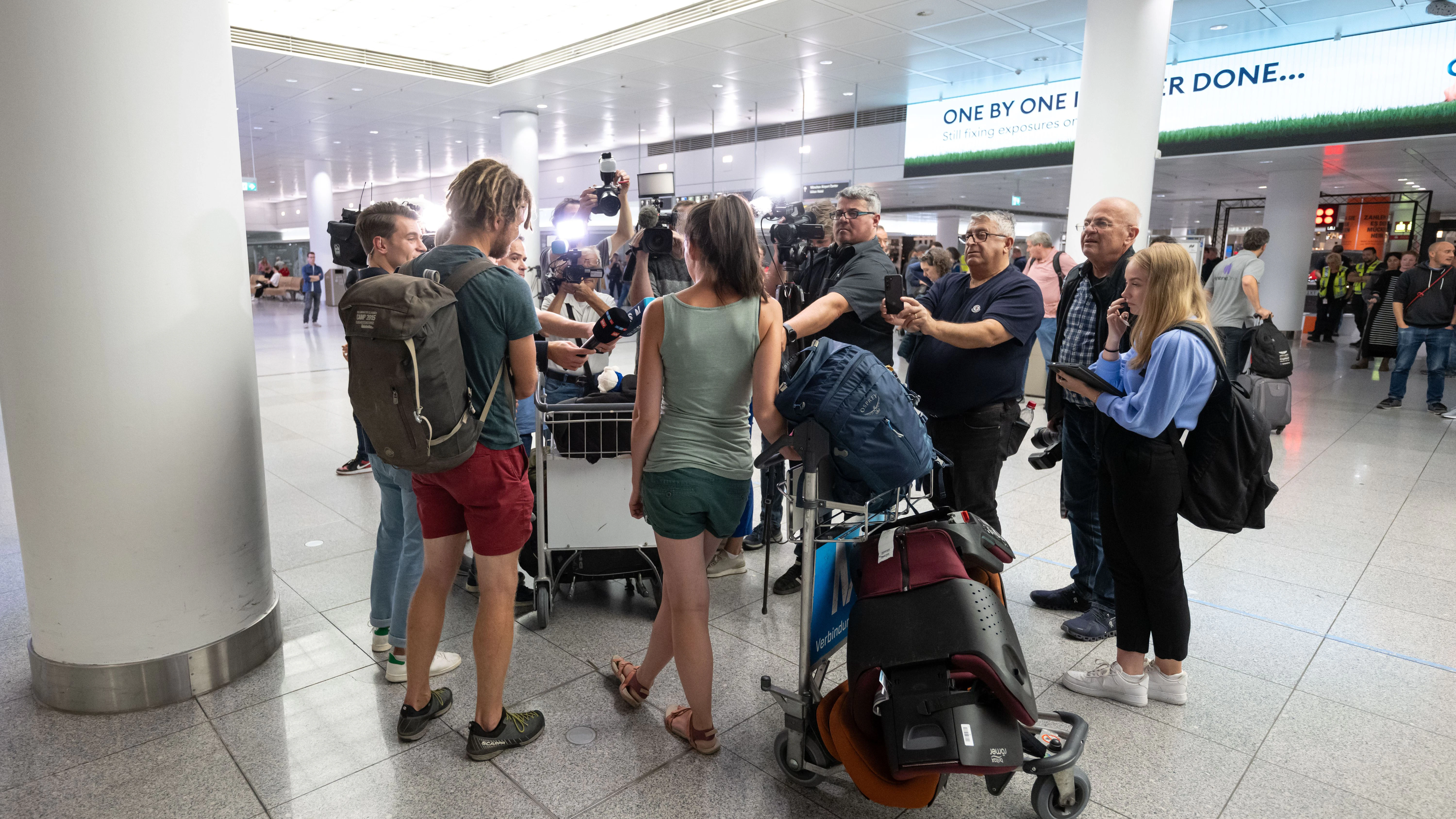 Die Touristen Franziska (M) und Alex sprechen mit Medien, nachdem sie mit einem von der Bundesregierung organisierten Sonderflug der Lufthansa aus Tel Aviv, Israel, am Flughafen München ankamen.&nbsp;