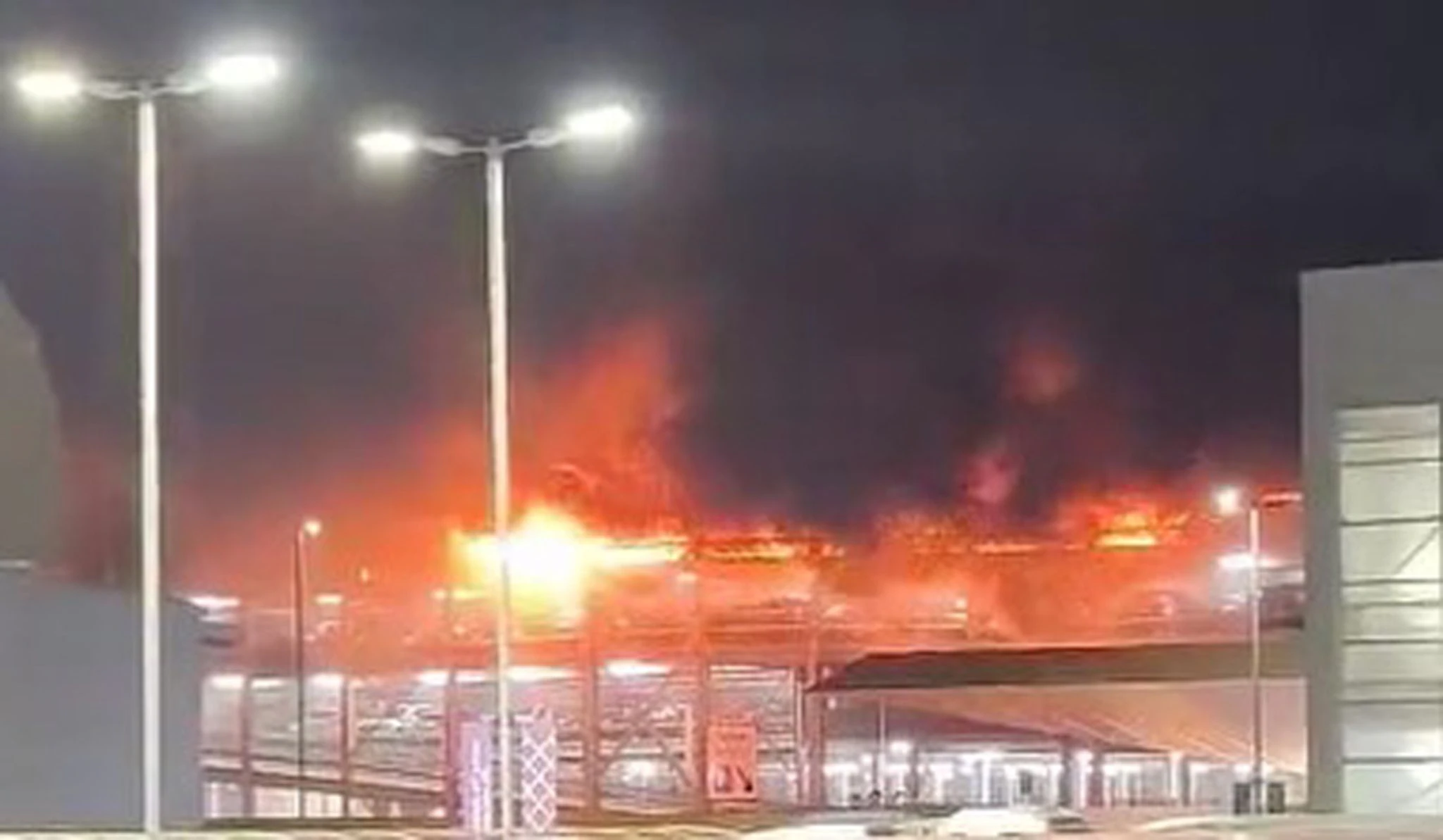 HANDOUT - Flammen schlagen aus der obersten Etage eines mit vielen Autos besetzten Parkhauses am Londoner Flughafen Luton (Screenshot aus einem bei X geposteten Video).  
