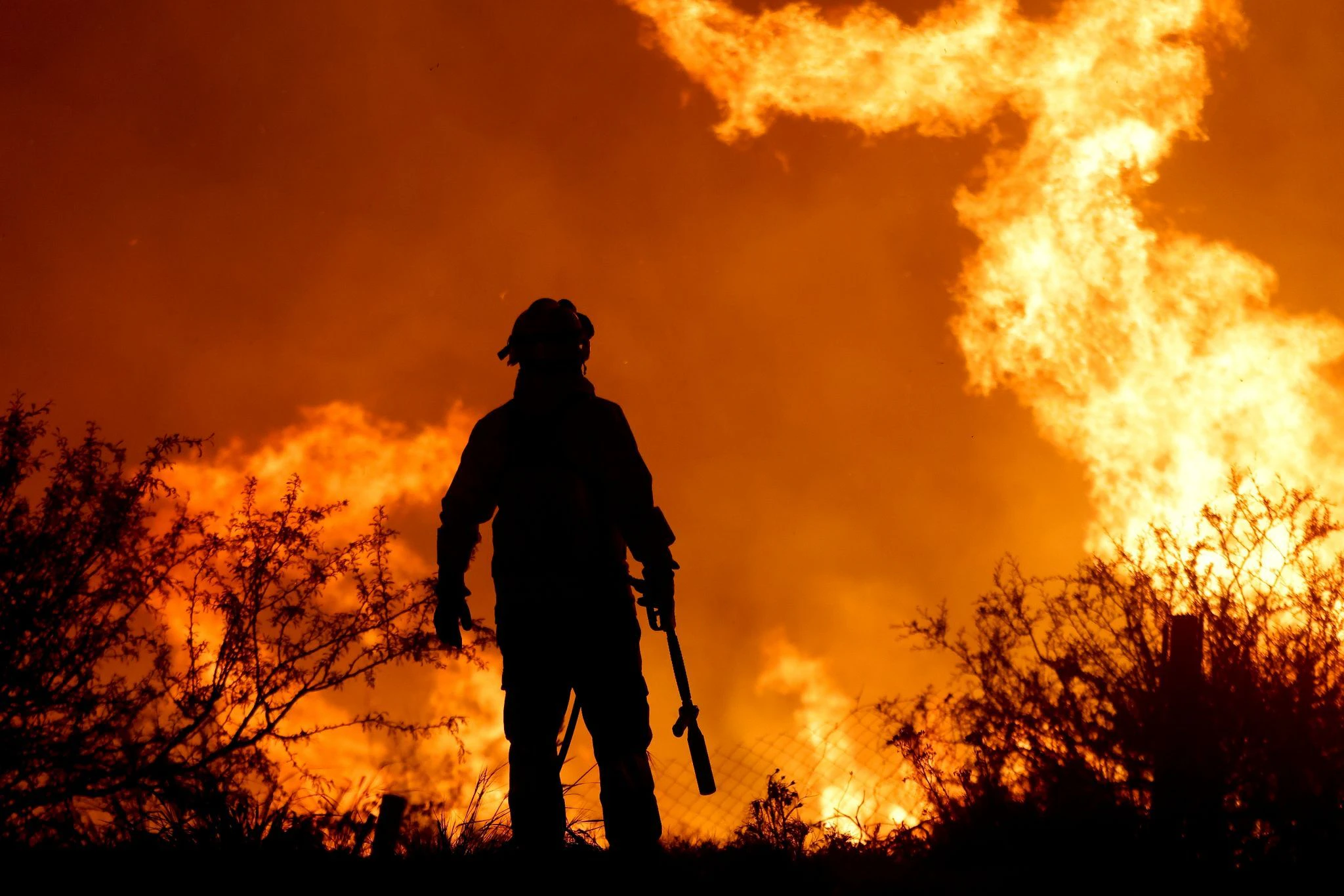 Ein argentinischer Feuerwehrmann wird von den Flammen eines Waldbrandes am Stadtrand von Villa Carlos Paz umrahmt.  