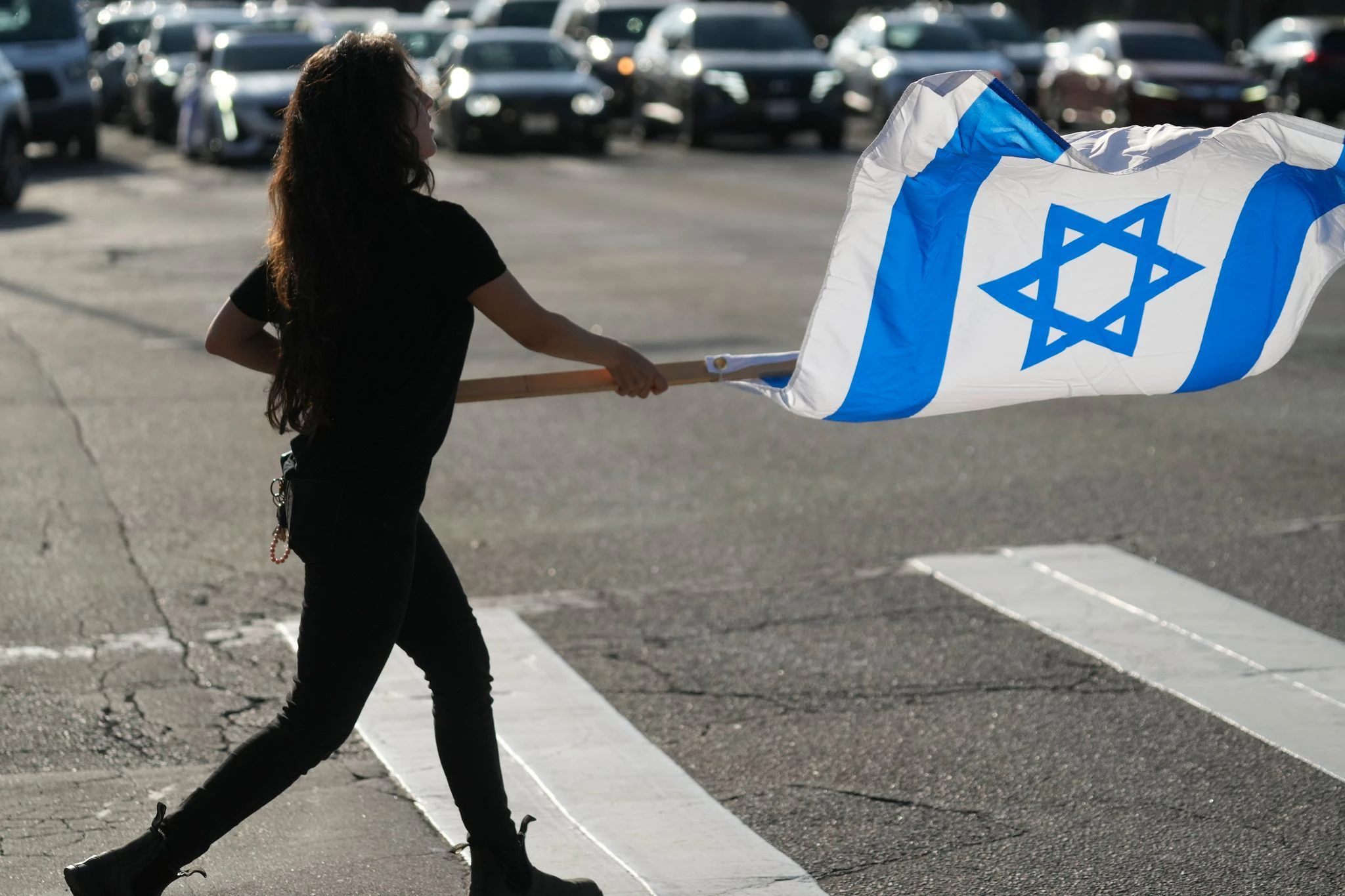 Eine Frau schwenkt die israelische Fahne als Symbol für ihre Unterstützung: In Los Angeles demonstrieren am Abend Menschen gegen den Terrorangriff der Hamas auf Israel.  