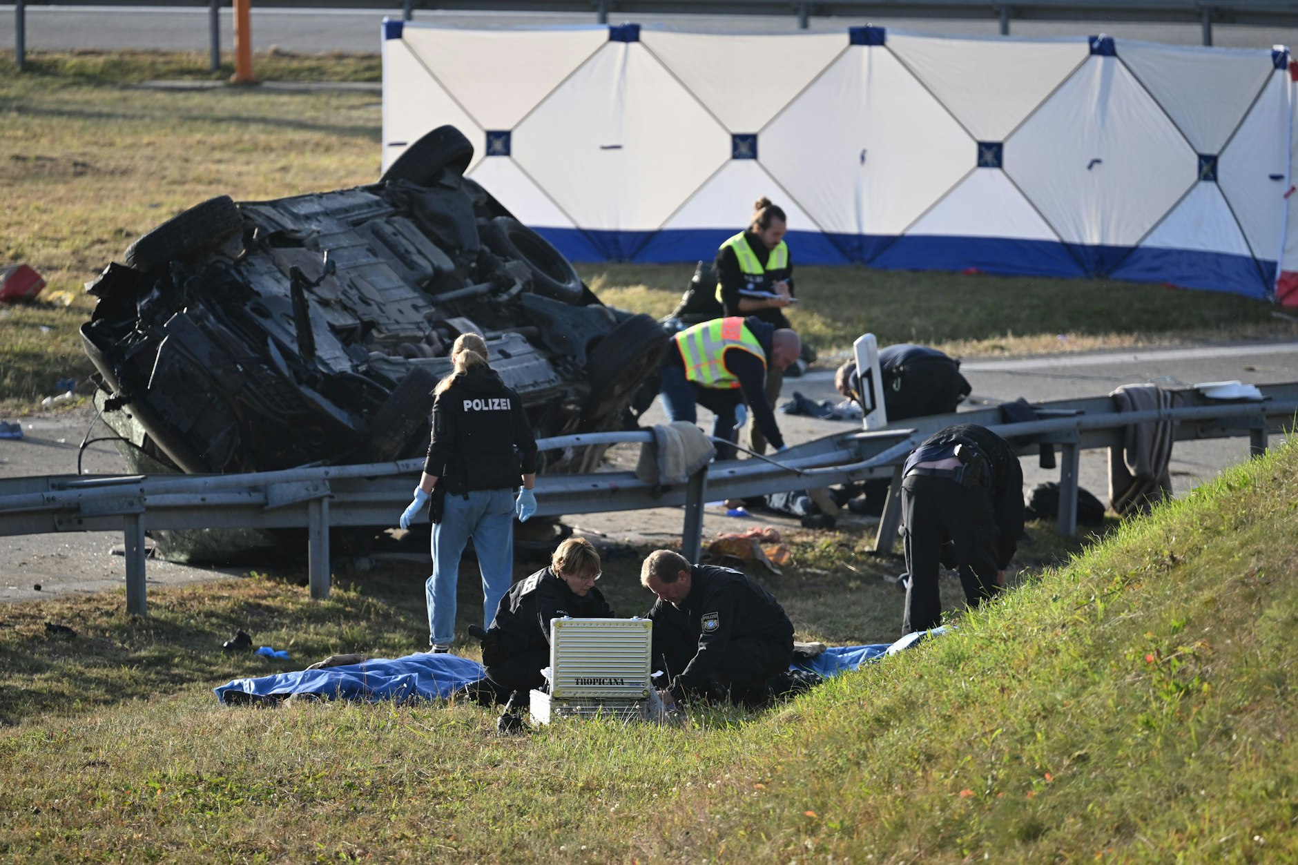 Rettungskräfte und Polizisten stehen am umgestürzten Fahrzeug. 