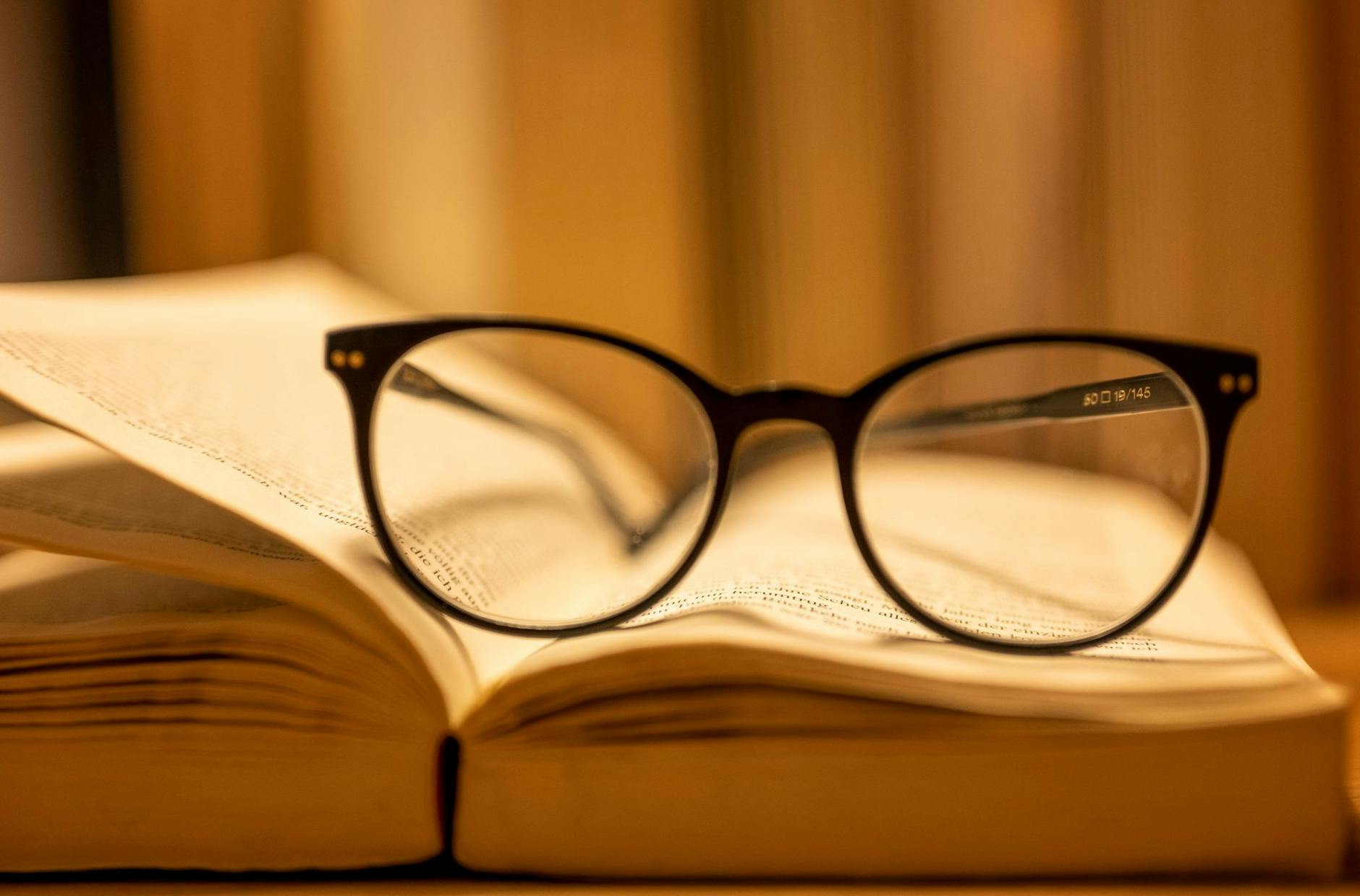 ARCHIV - Eine Lesebrille liegt auf einem geöffneten Papierbuch. ion