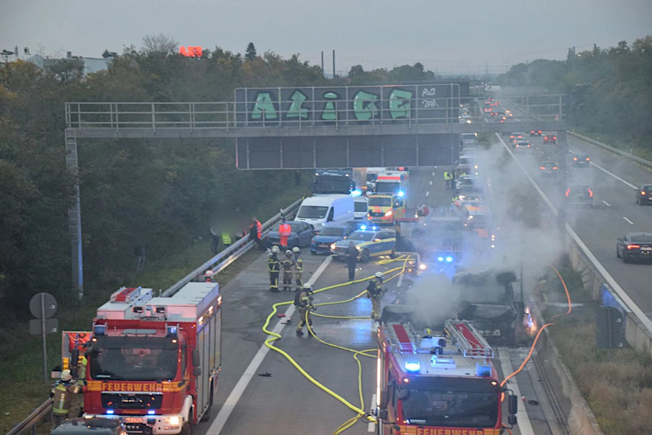 Zahlreiche Einsatzkräfte der Feuerwehr bei Löscharbeiten an einem brennenden Fahrzeug auf der A5.  