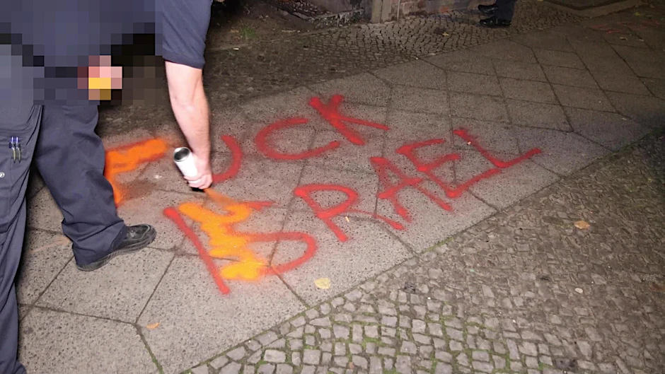 Ein Berliner Polizist übermalt eine israelfeindliche Schmiererei.