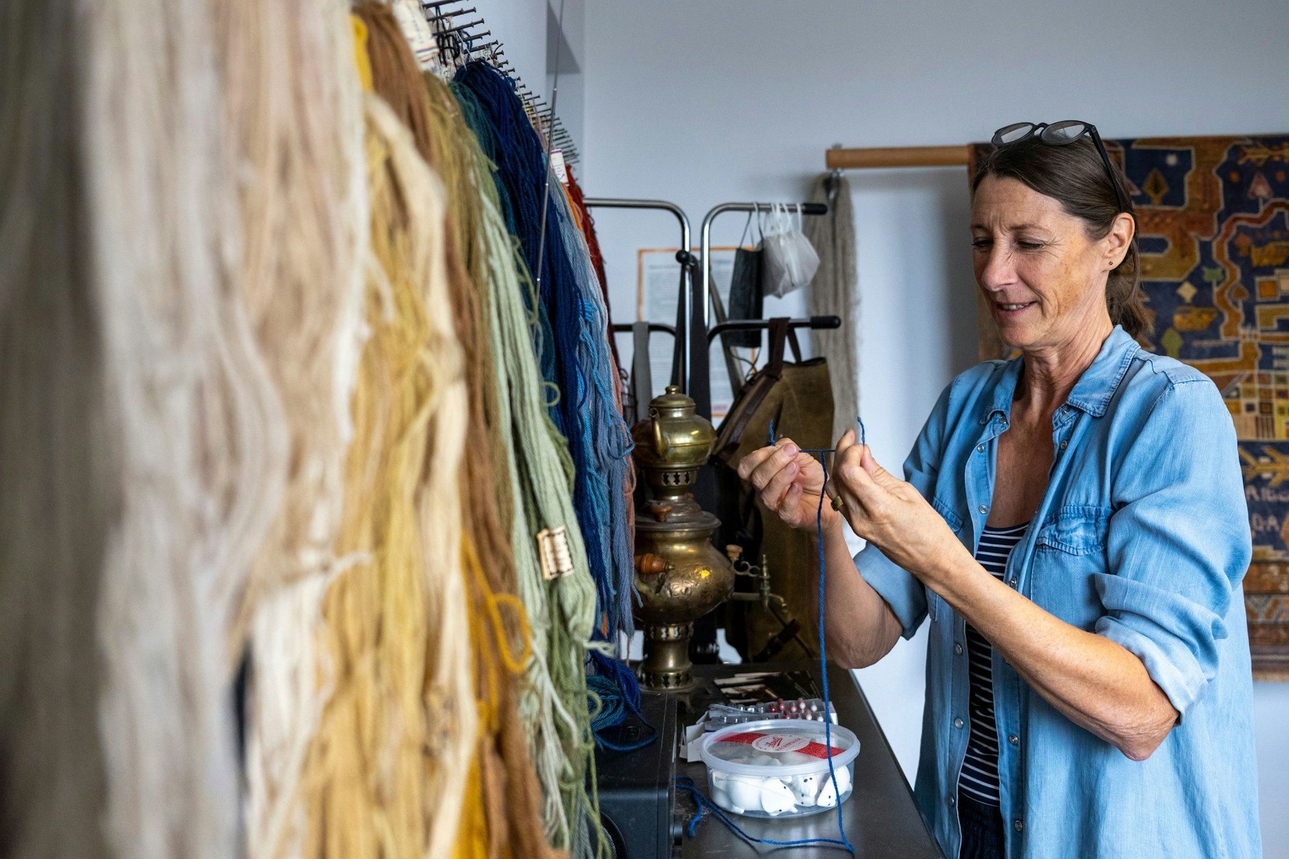 Claudia Diedenhoven sucht in ihrer Werkstatt nach passender Wolle für die Reparatur eines alten Orientteppiches.