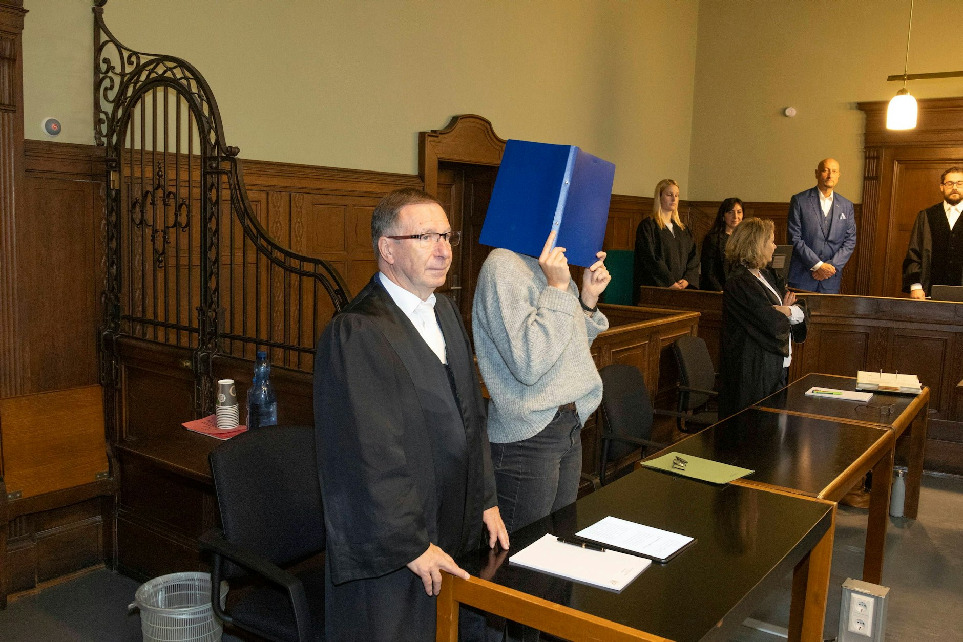 Der Platz an der Anklagebank ist noch leer. Der Arzt kam erst, als die Fotografen aus dem Gerichtssaal waren. Neben dem leeren Stuhl steht die mitangeklagte Krankenschwester.