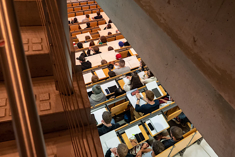 Studierende nehmen in einem Hörsaal an einer Vorlesung teil.  