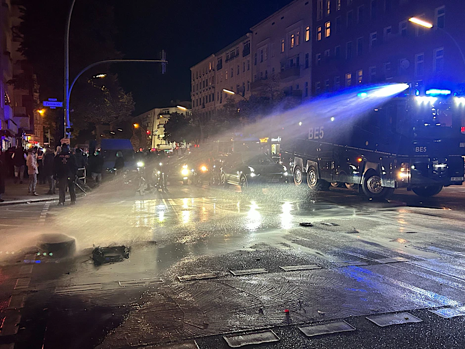Mit einem Wasserwerfer löscht die Polizei während einer verbotenen Pro-Palästina-Demonstration auf der Sonnenallee im Bezirk Neukölln brennende Autoreifen.
